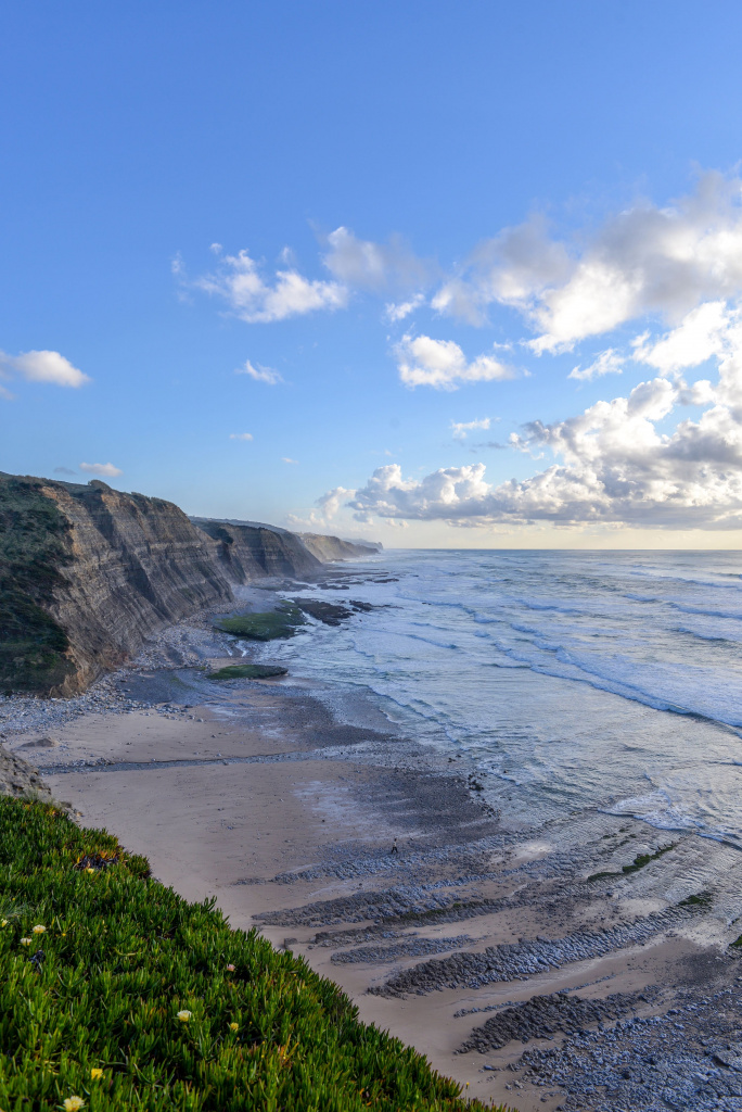 vertical-picture-beach-surrounded-by-sea-cliffs-sunlight-cloudy-sky (1) (1).jpg